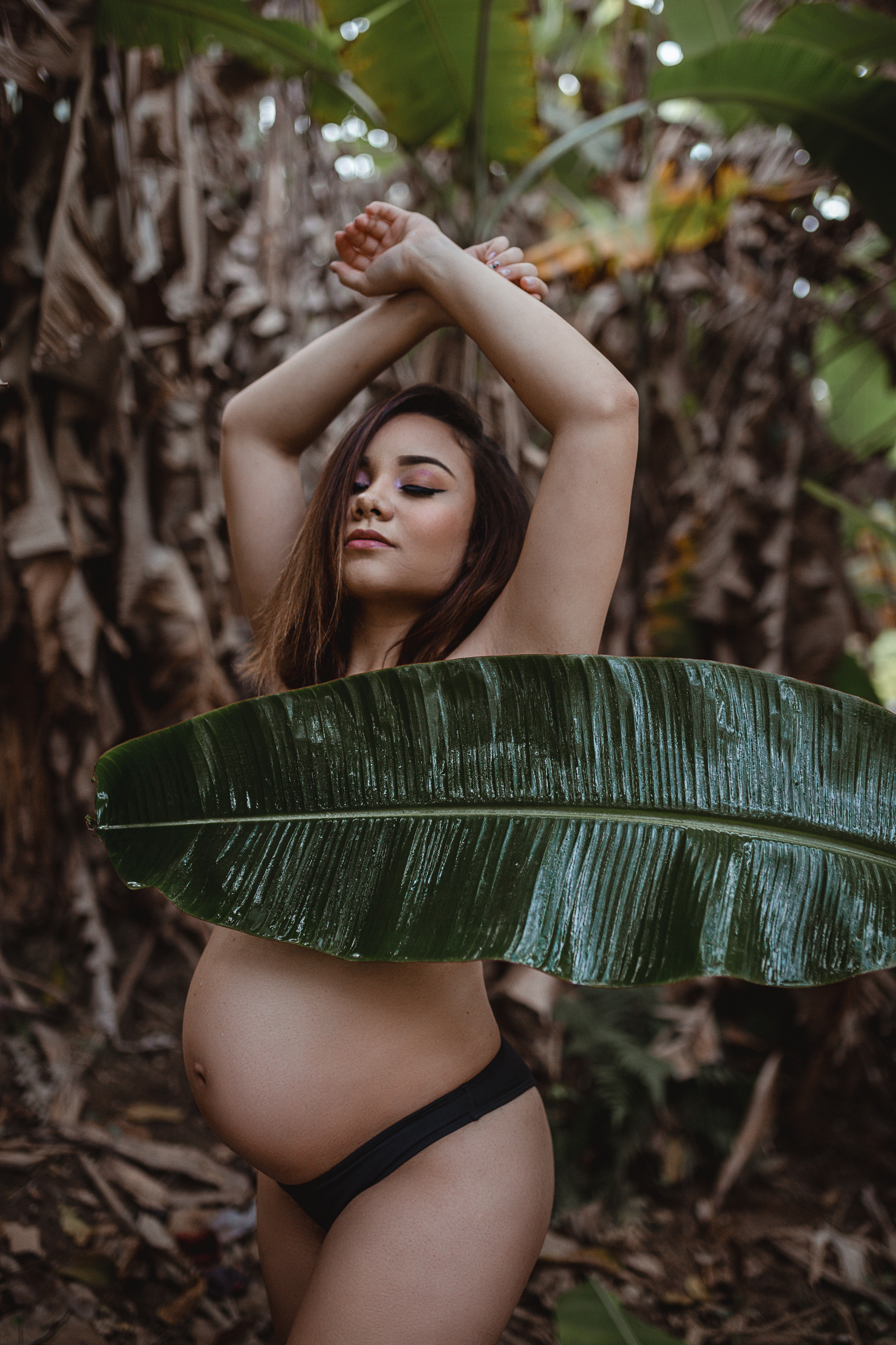 Maternity Shoot of a Pregnant Woman  Hiding her Top with Banana Leaf